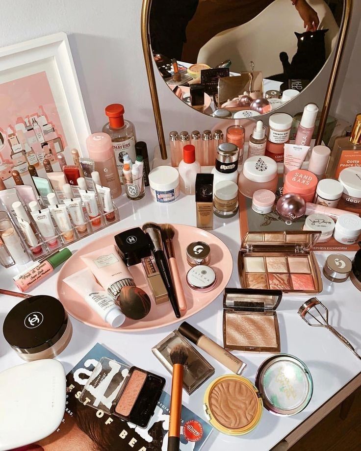 Make-up en huidverzorging uitgestald op de visagietafel, met een ronde gouden spiegel