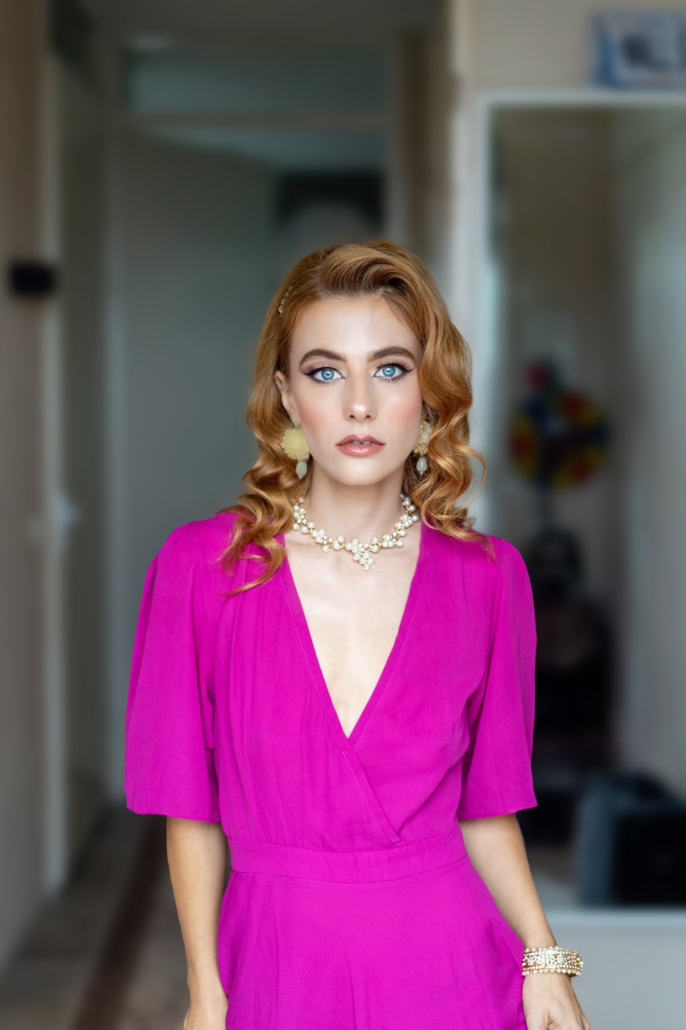 Model in een magenta jurk met opgemaakte ogen en lange krullen